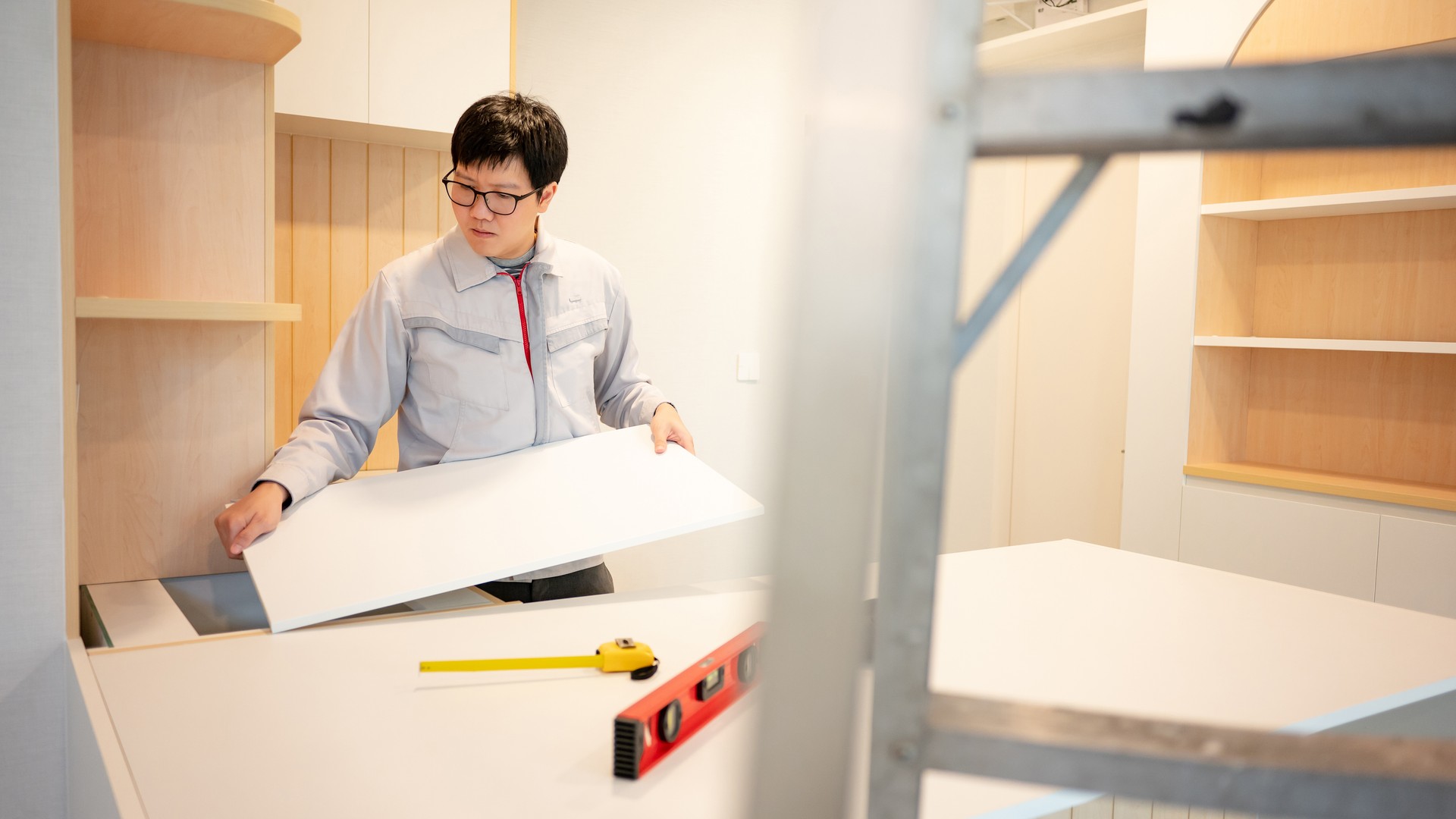 Asian male furniture assembler installing cabinet panel