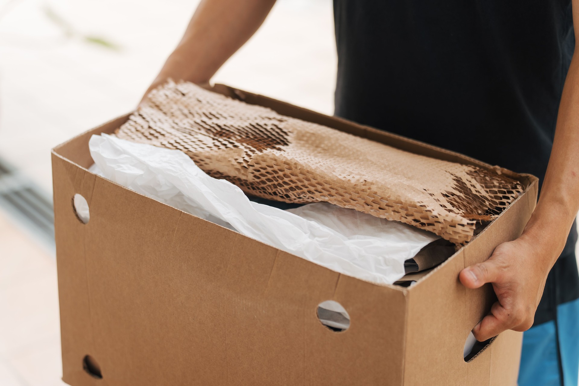 Asian man's hands holding a carton box prepared for recycling or reuse.